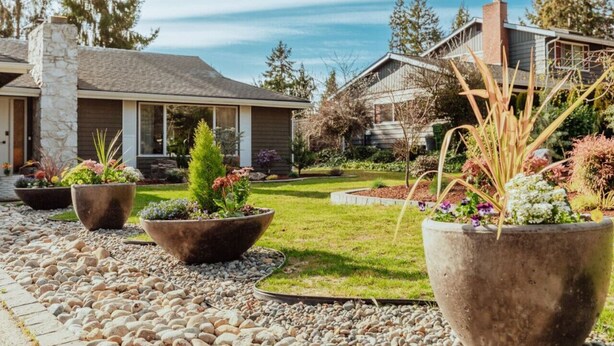 A residential area with houses, a stone chimney, and a garden with large planters.