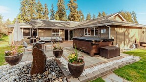 A house with a patio area featuring outdoor furniture, a hot tub, and potted plants.