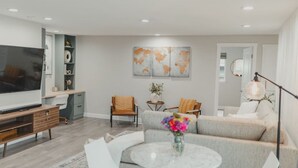 A modern living room with a flat-screen TV, grey sofas, a coffee table, and a world map artwork on the wall.
