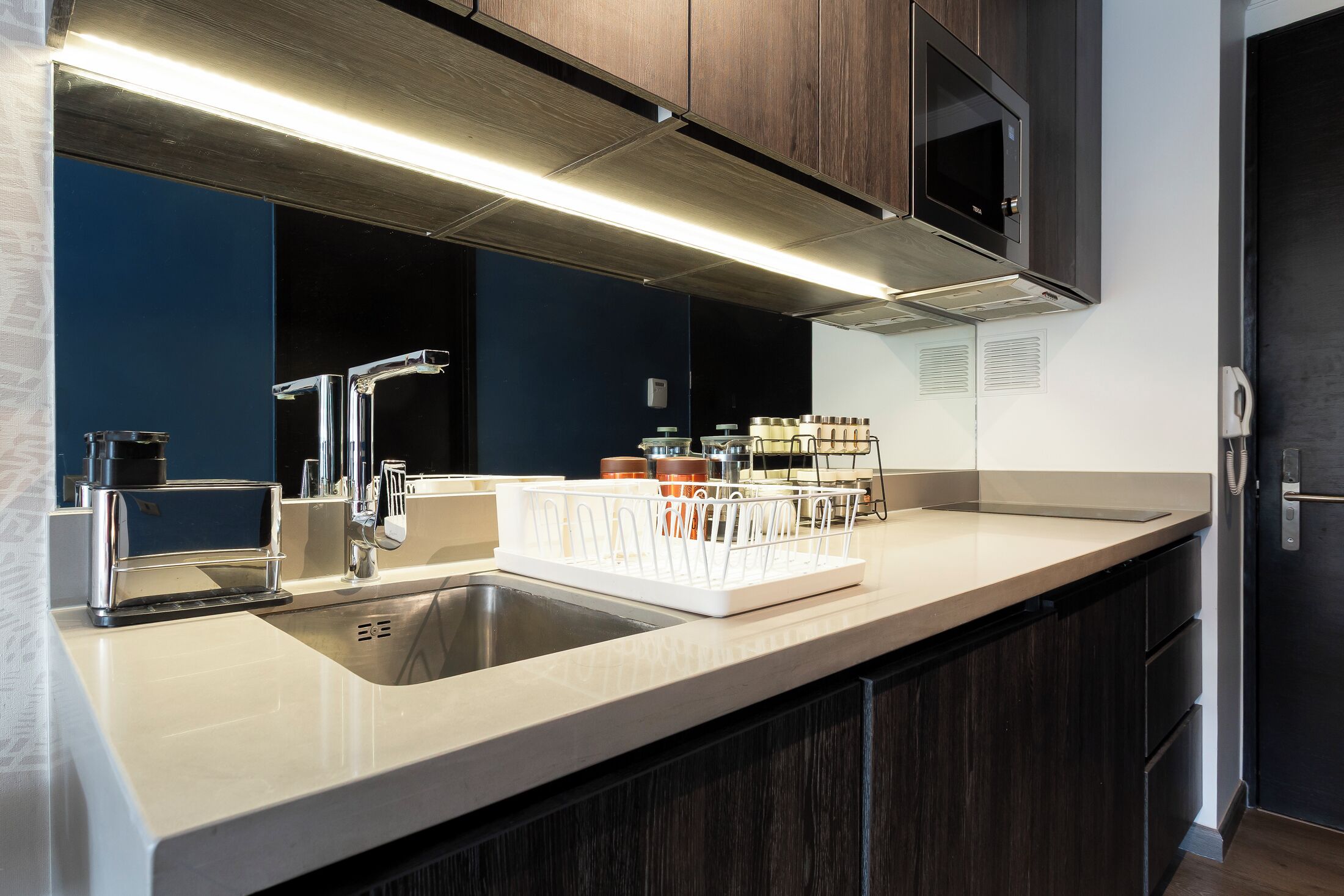 A modern kitchen with a stainless steel sink, a microwave, and a built-in oven.