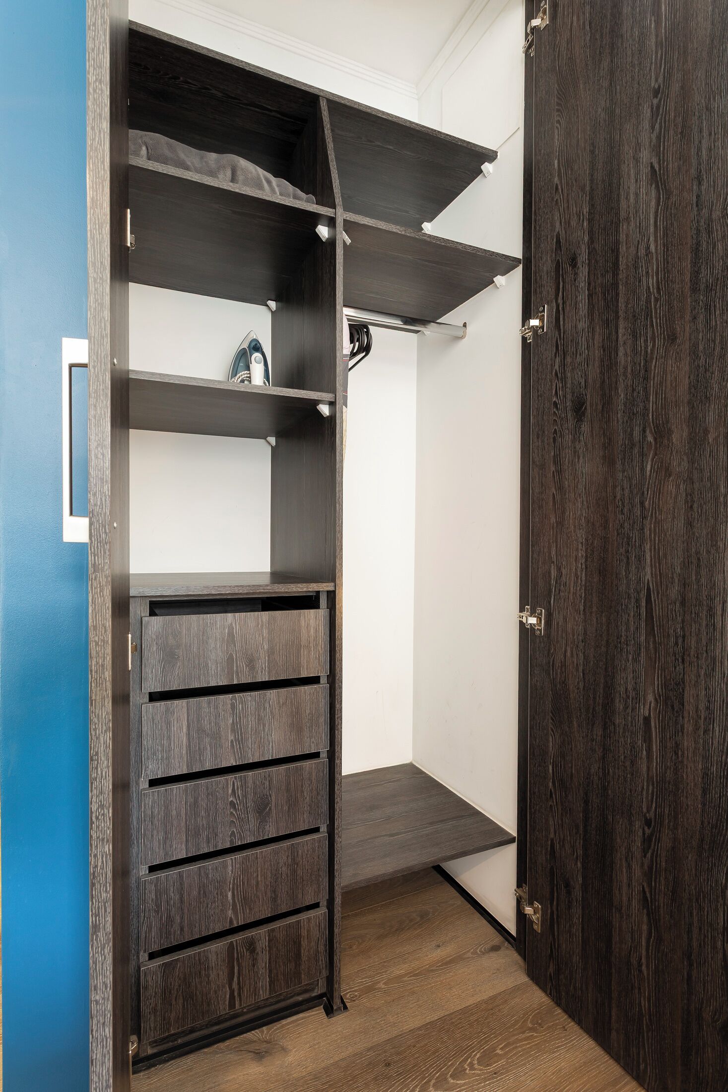 A closet with dark wood shelving, a hanging rod, and a sliding door.