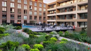 Un hotel modern amb diverses plantes, una piscina i una zona de jardí paisatgística.