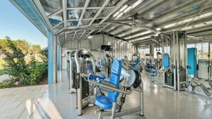 Ein modernes Fitnessstudio mit verschiedenen Trainingsgeräten und einer Glasdecke.