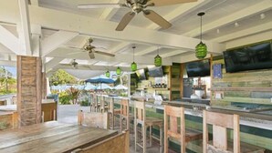 Ein Restaurant im Freien mit Holztischen und -stühlen, Deckenventilatoren und grünen Laternen.