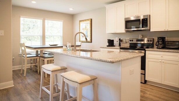 A modern kitchen with white cabinets, stainless steel appliances, and a central island with bar stools.