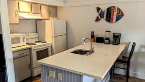 Une cuisine moderne avec des appareils électroménagers blancs, un îlot central doté d’un évier et un pare-feu à rayures.