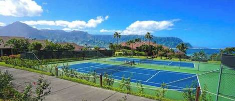 Un court de tennis offrant une vue sur l’océan et les montagnes.