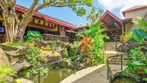 Resort tropical com cachoeira, degraus de pedra e vegetação exuberante.