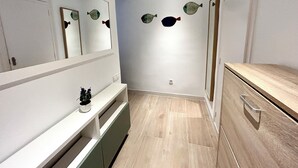 Ein modernes Badezimmer mit Spiegel, Holzkosmetikschrank und Wandbildern von Fischen.