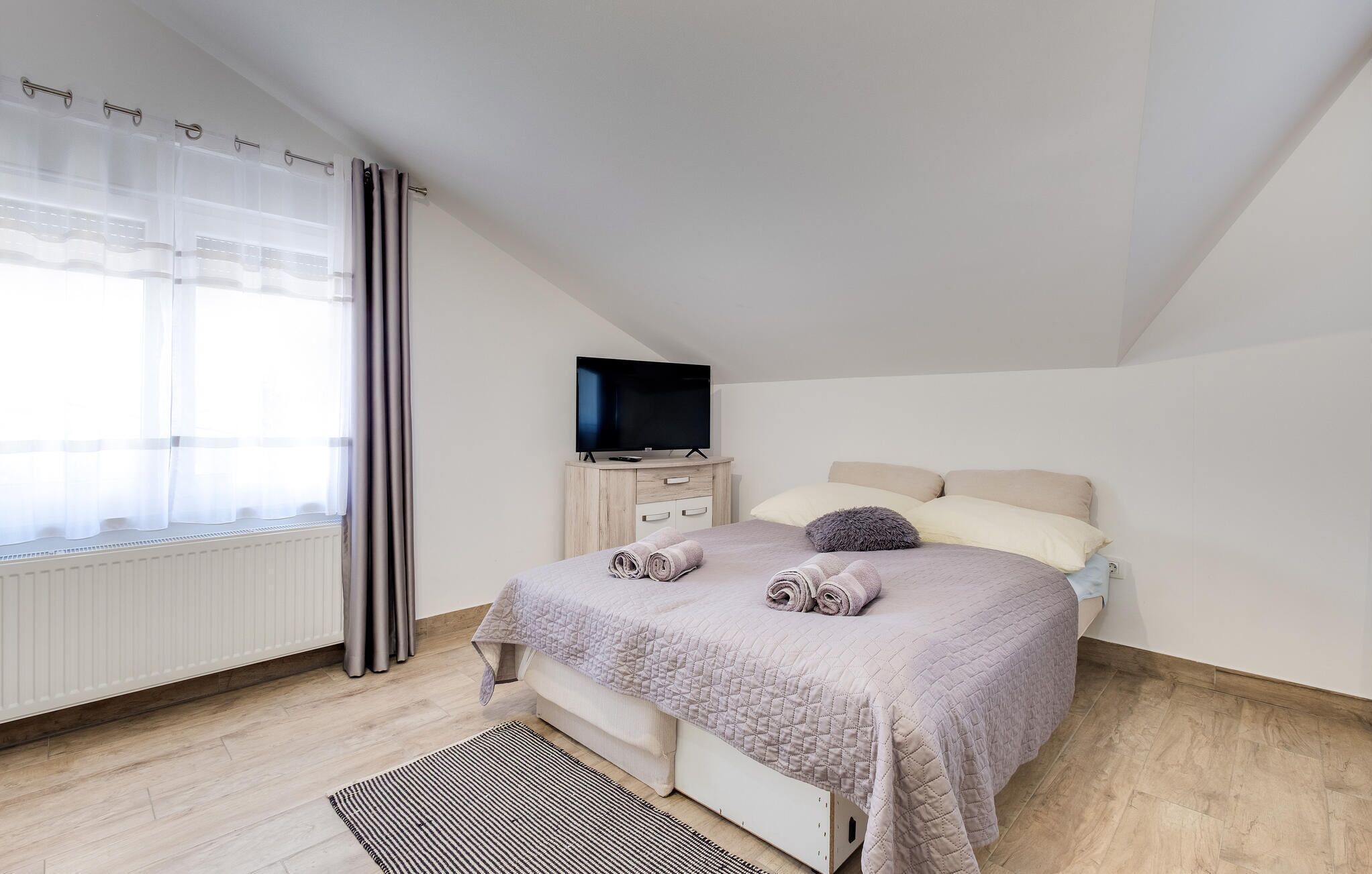 Un dormitorio con cama, televisor y radiador.