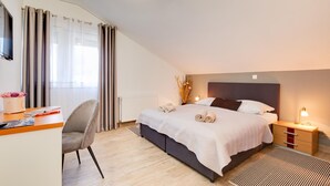 Een moderne slaapkamer met een bed, nachtkastjes, een bureau en een stoel.