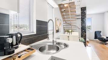 A modern kitchen with a built-in sink, a coffee maker, and a wooden shelf.