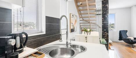 A modern kitchen with a built-in sink, a coffee maker, and a wooden shelf.