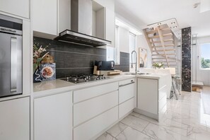 A modern kitchen with a gas stove, a built-in oven, and a stainless steel refrigerator.
