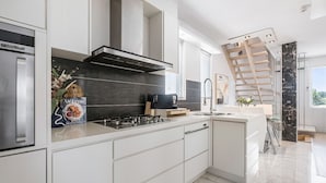 A modern kitchen with a gas stove, a built-in oven, and a stainless steel refrigerator. - The Red Ember Retreat (Caulfield North)