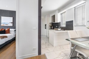 A modern apartment with a bedroom, kitchenette, and dining area.