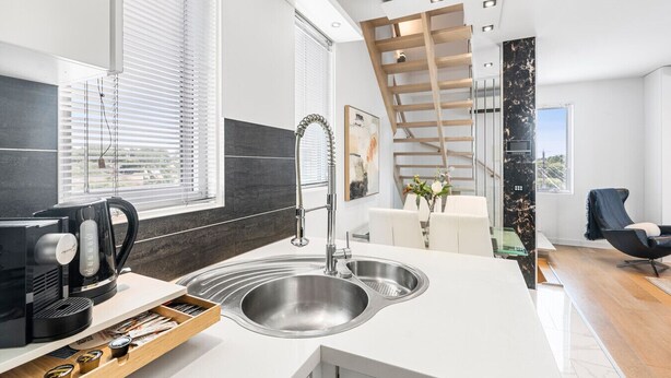 A modern kitchen with a built-in sink, a coffee maker, and a wooden shelf. - The Red Ember Retreat (Caulfield North)