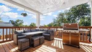 A covered deck with a grill, wicker furniture, and a hanging plant. - Pool, Sauna, Work out area, ping pong, King Bed.  So Many Amenities!!! (Omaha)