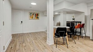 Un intérieur moderne avec un coin repas comprenant une table ronde et des chaises noires et rouges, une porte blanche et un plancher en bois.