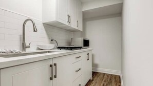Une cuisine moderne avec des meubles blancs, un robinet en acier inoxydable et un four à micro-ondes.