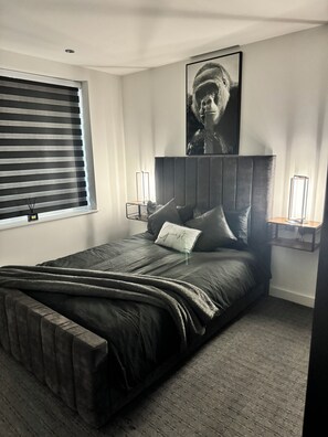 Relax in a serene bedroom with a large bed, unique pillow, and framed artwork.