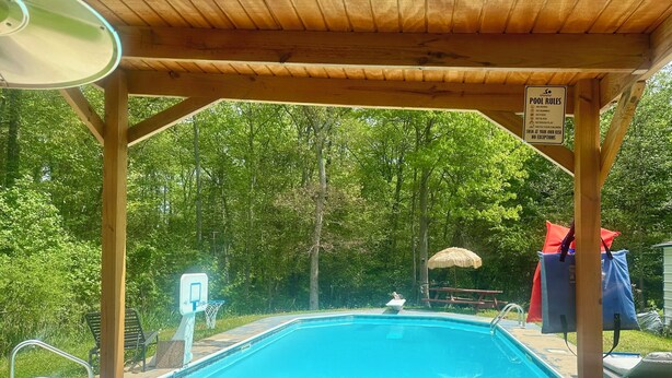 Eine Holzterrasse mit Pool, Sprungbrett und einem Schild, das Poolregeln auflistet.