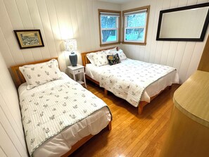 Een slaapkamer met twee bedden, een nachtkastje, een lamp en een raam.