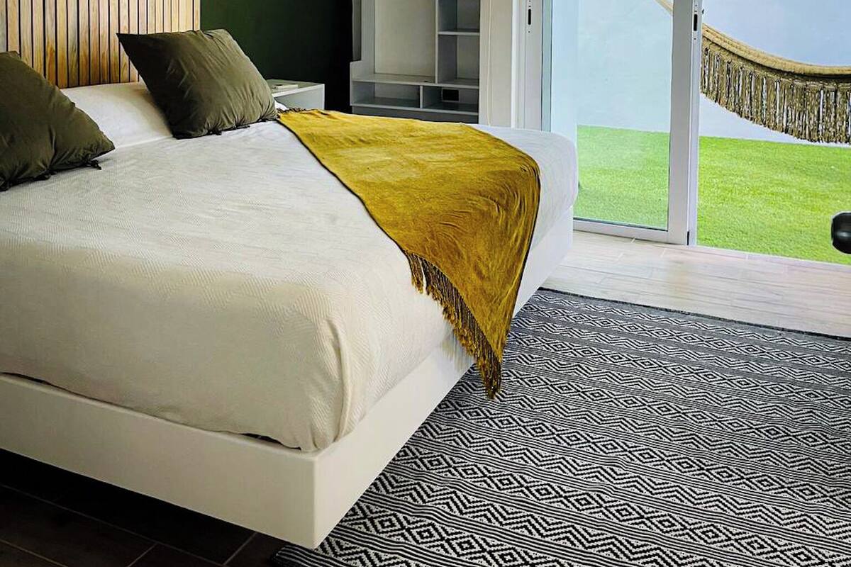 A bedroom with a bed, a ceiling fan, a window, and a view of a grassy area.