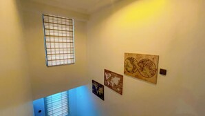 Ein Zimmer mit Fenster, Jalousien, einem Wandthermostat und drei gerahmten Bildern.
