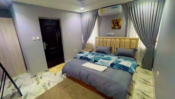 Ein Schlafzimmer mit einem Bett, einem Sessel, einer Klimaanlage und einer Tür.