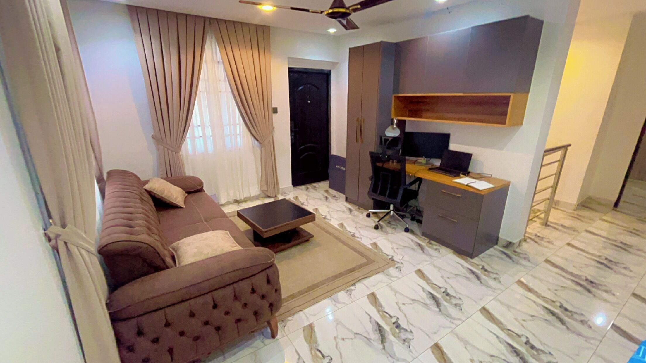 Un salon comprenant un canapé, une table basse, un bureau avec un ordinateur et une armoire.