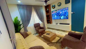 Ein Wohnzimmer mit Sofa, Sesseln, Couchtisch, Fernseher und Deckenventilator.