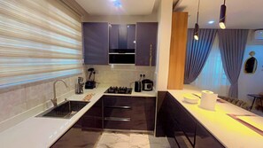 Cocina moderna con estufa a gas, pileta y mesada con cafetera y un bowl.