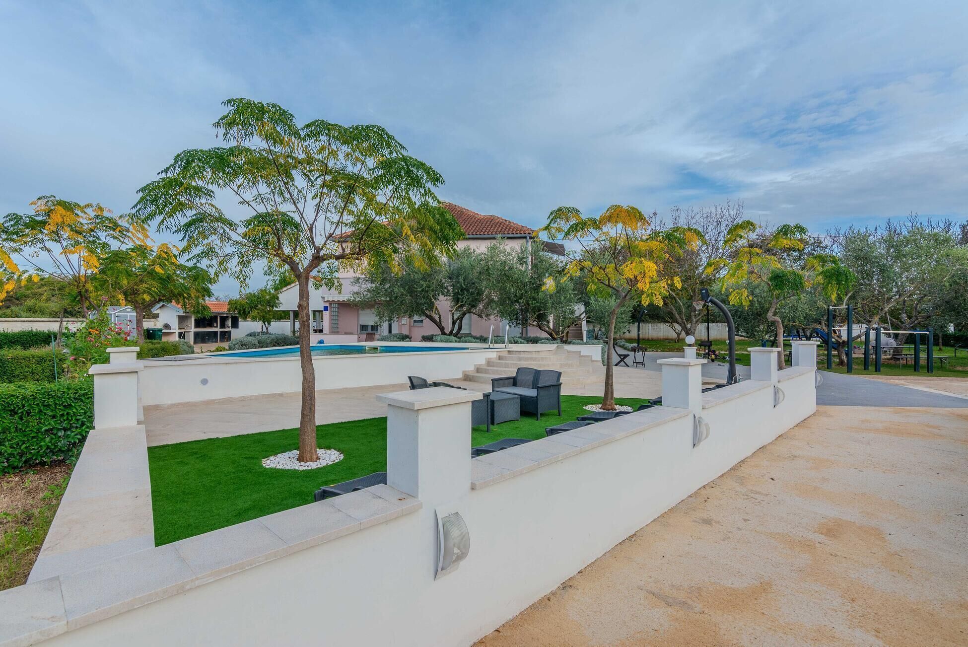 A landscaped outdoor area with a pool, seating, and a playground.