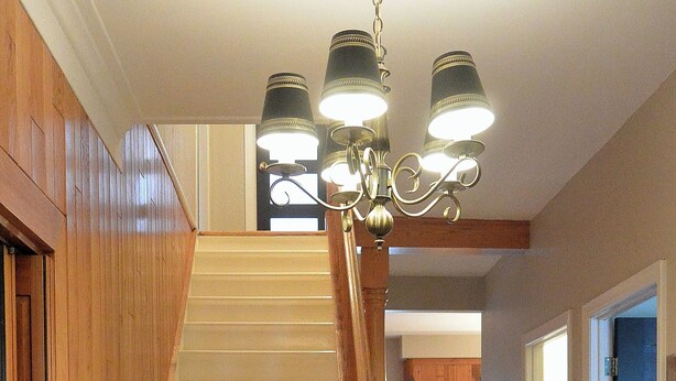 Una escalera de madera con un aplique moderno en la parte superior.