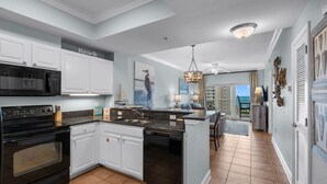 A kitchen with white cabinets, a black stove, and a dishwasher. - Lazy River, 3 Pools - Crystal Tower - Free Daily Activities & Beach Service! (Gulf Shores)
