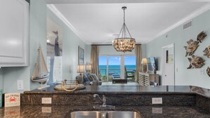 A kitchen with a granite countertop, stainless steel sink, and a chandelier. - Lazy River, 3 Pools - Crystal Tower - Free Daily Activities & Beach Service! (Gulf Shores)