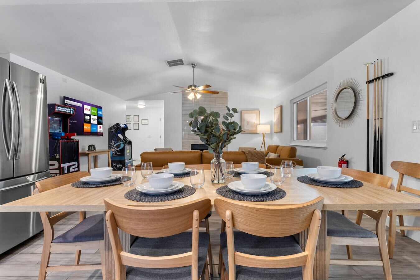Une cuisine moderne avec une table à manger pour quatre personnes, un réfrigérateur et un téléviseur fixé au mur.