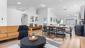 A spacious living area with a sofa, coffee table, and dining table with chairs.