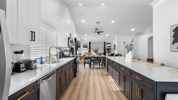 A modern kitchen with a central island, dark cabinetry, and a wooden floor.