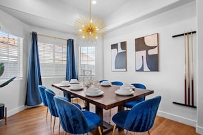 Un comedor con una mesa de madera, sillas azules y una obra de arte abstracta en la pared.