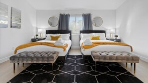 Une chambre d’hôtel avec deux lits, un tapis noir et blanc et un ventilateur de plafond.