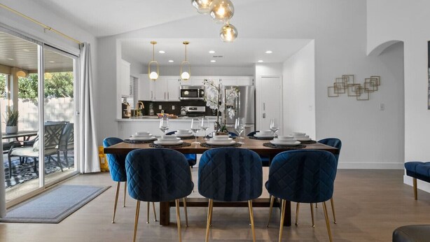 Un espace repas moderne avec une grande table, des chaises bleues et une cuisine en arrière-plan.