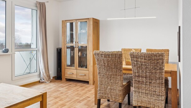 A dining area with a wooden cabinet, wicker chairs, and a table. - 1 bedroom cozy apartment in Anklam (Anklam)