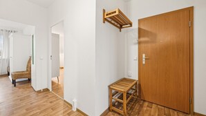 A hallway with a wooden door, a small wooden bench, and a wicker chair. - 1 bedroom cozy apartment in Anklam (Anklam)