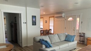 A living room with a sofa, a coffee table, and a dining area in the background. - Music Place Guest House (Maple Falls)