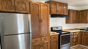 A kitchen with wooden cabinets, a stainless steel refrigerator, a stove, and a microwave. - Music Place Guest House (Maple Falls)