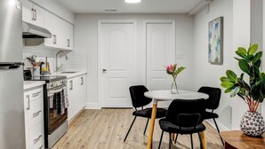 A modern kitchen with white cabinetry, a built-in oven, and a round dining table with black chairs. - Cozy 1-bedroom with Full Kitchen, workspace, WiFi and AC in charming Mississauga (Mississauga)