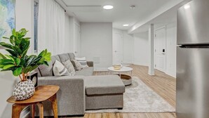 Een moderne woonkamer met een grijze bank, een houten salontafel en een kamerplant.