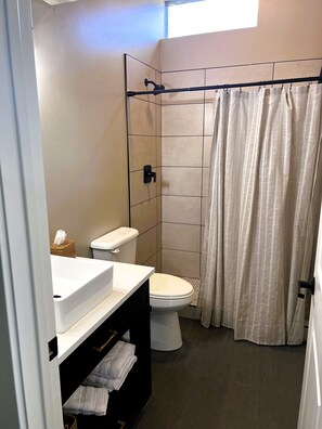 Een badkamer met toilet, wastafel en douche.